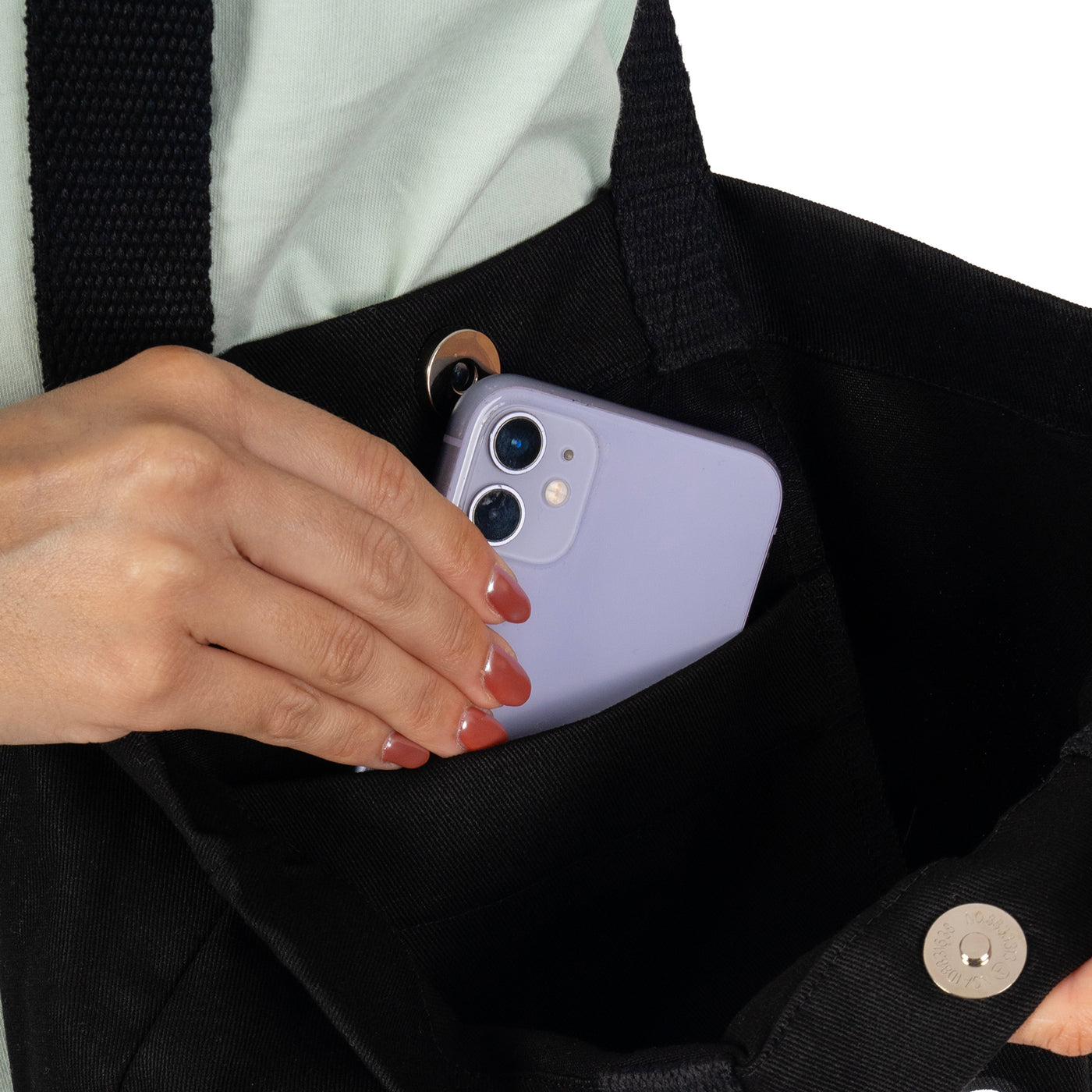 Close up of skater tote bag interior with hand placing phone in inner pocket american socks