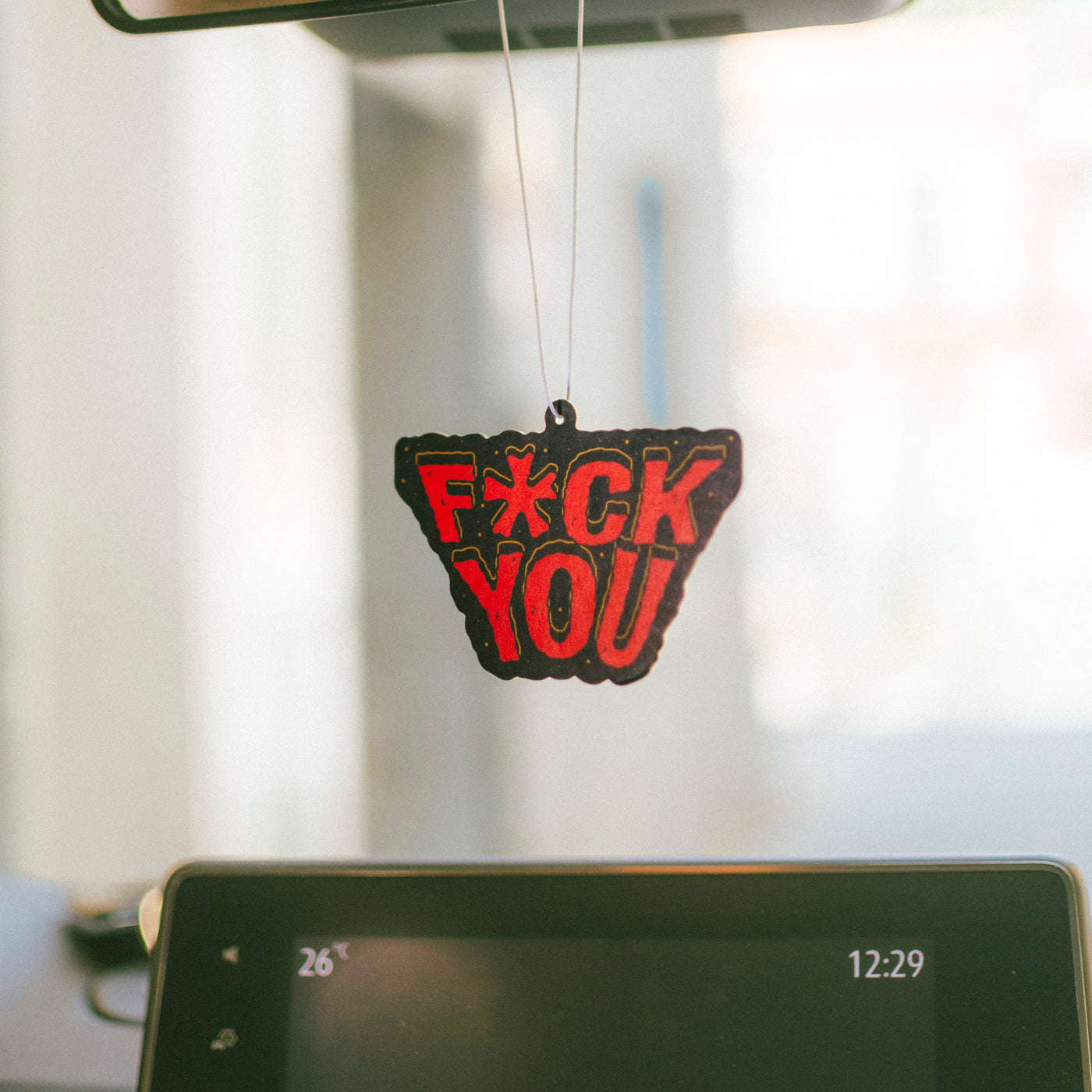 Bold punk 'fuck you' air freshener hanging from car rearview american socks 