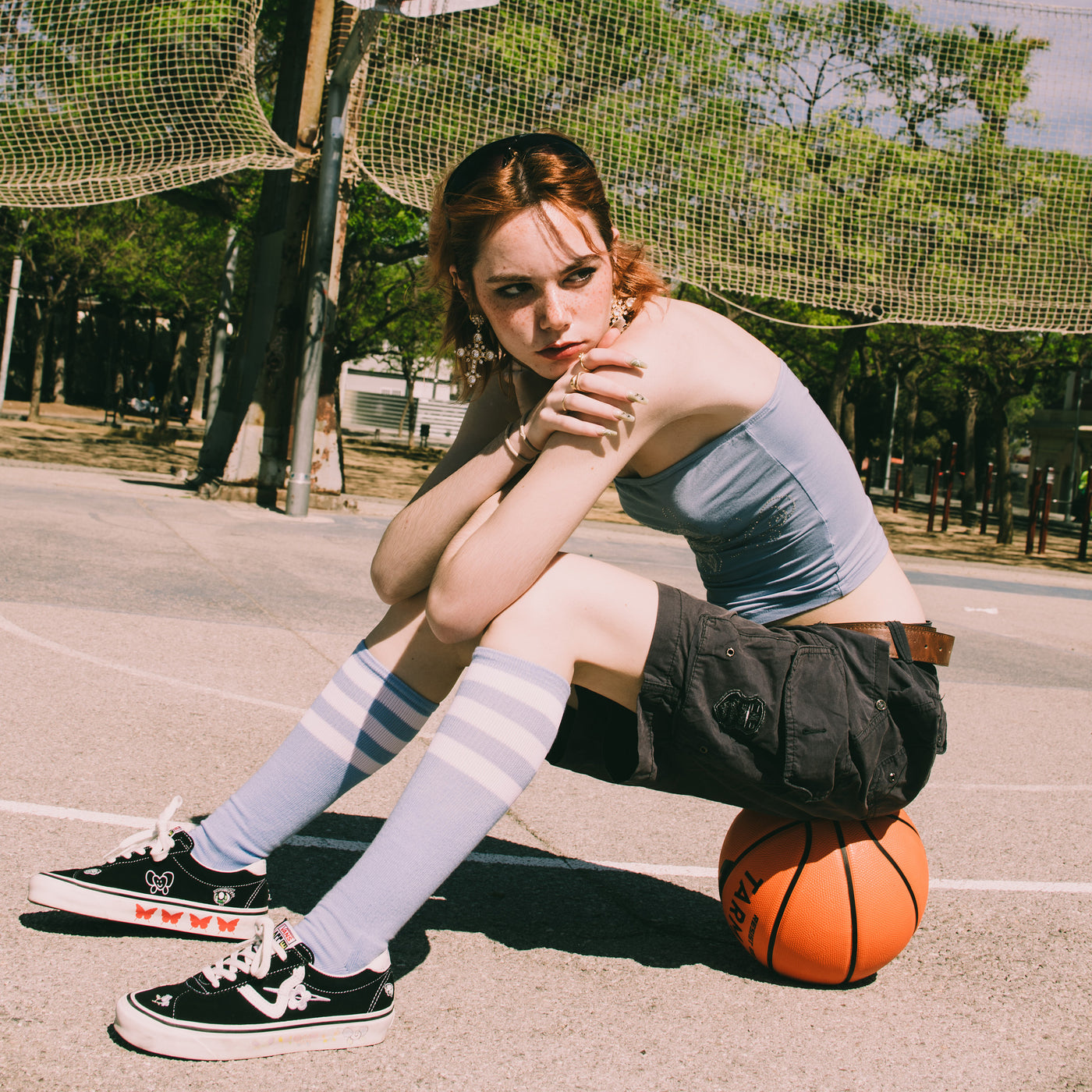 Person sitting on basket ball wearing light blue knee high socks american socks