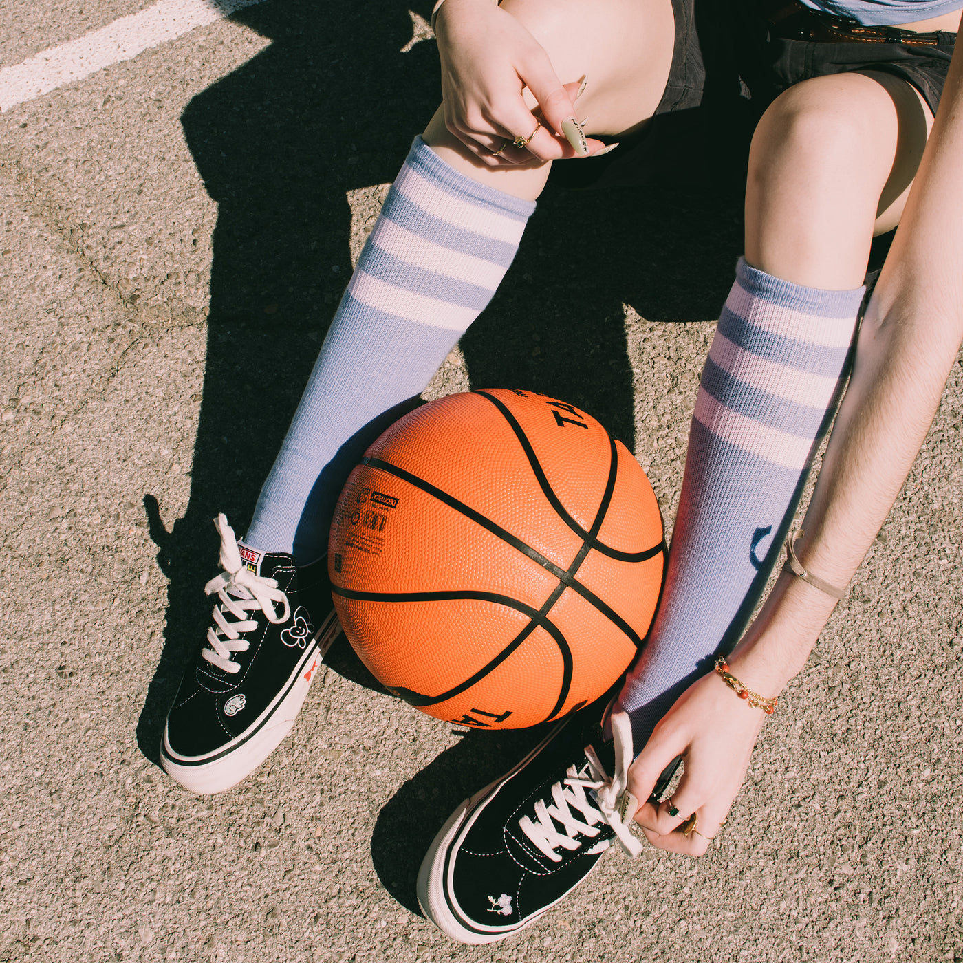 Legs wearing light blue knee high socks while holding a basketball between them american socks