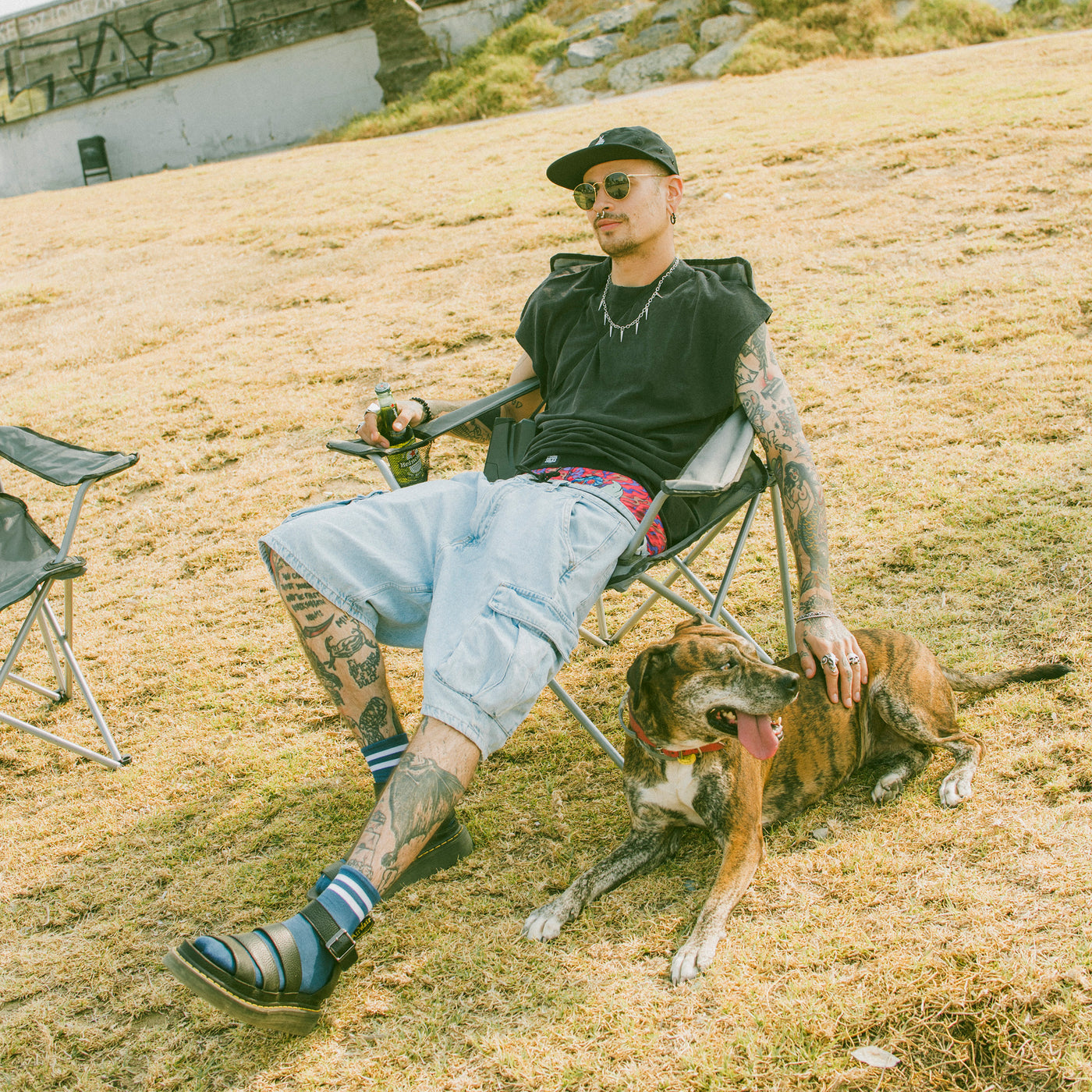 Man sitting outdoors wearing skate clothing and blue ankle high socks while petting a dog american socks