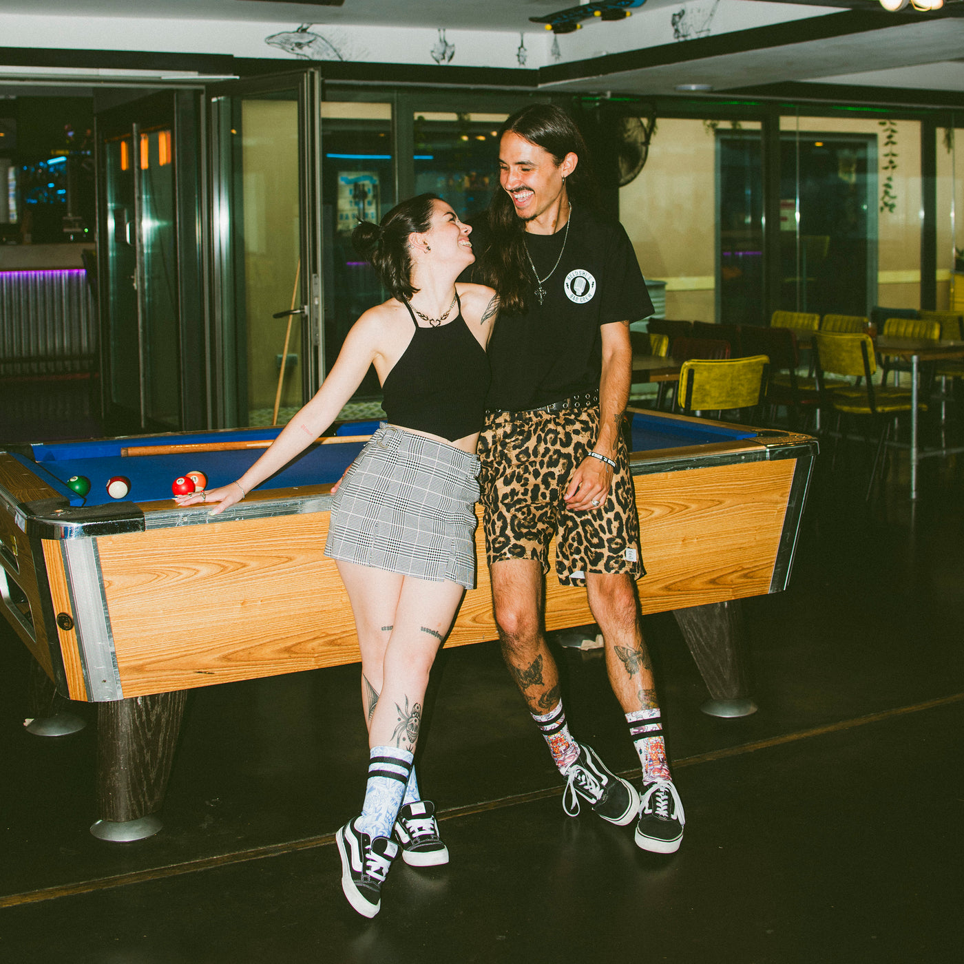 Man and woman leaning on a pool table wearing streetwear clothing and cool socks american socks